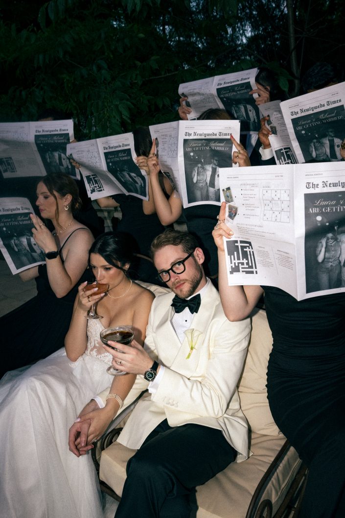 Wedding reception party with guests holding custom newspapers, editorial wedding storytelling