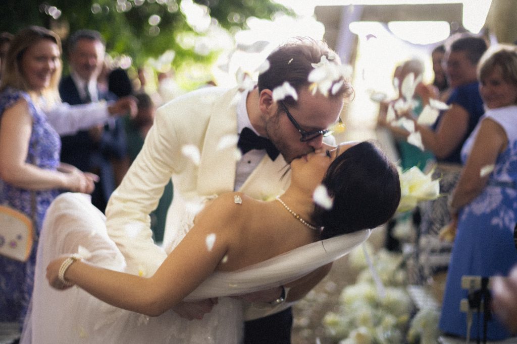 wedding dip kiss during petal exit in Chateau des Barrenques, natural moment guided by invisible direction
