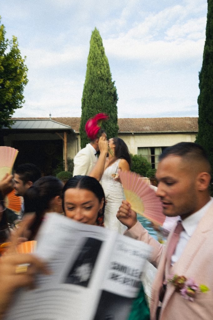 wedding couple kissing in background with guests moving in foreground motion blur documentary photography